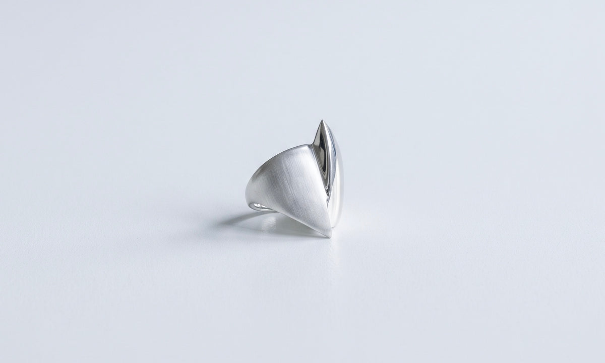 a finished fenda ring in brushed white metal, its curved form rising from the band