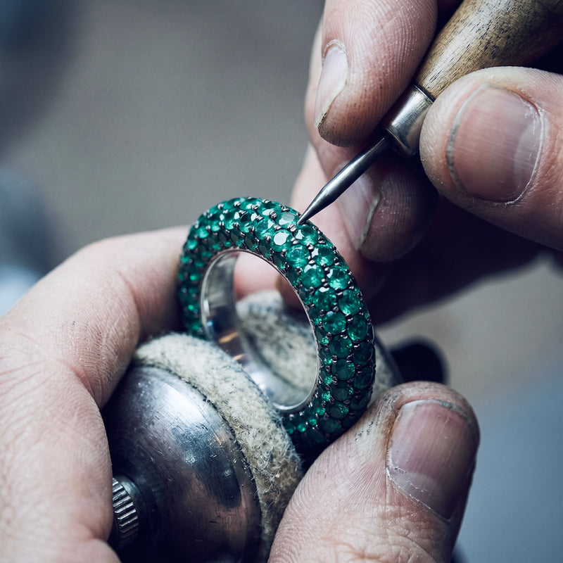 a ring of green stones held between the fingers as each stone is set by hand
